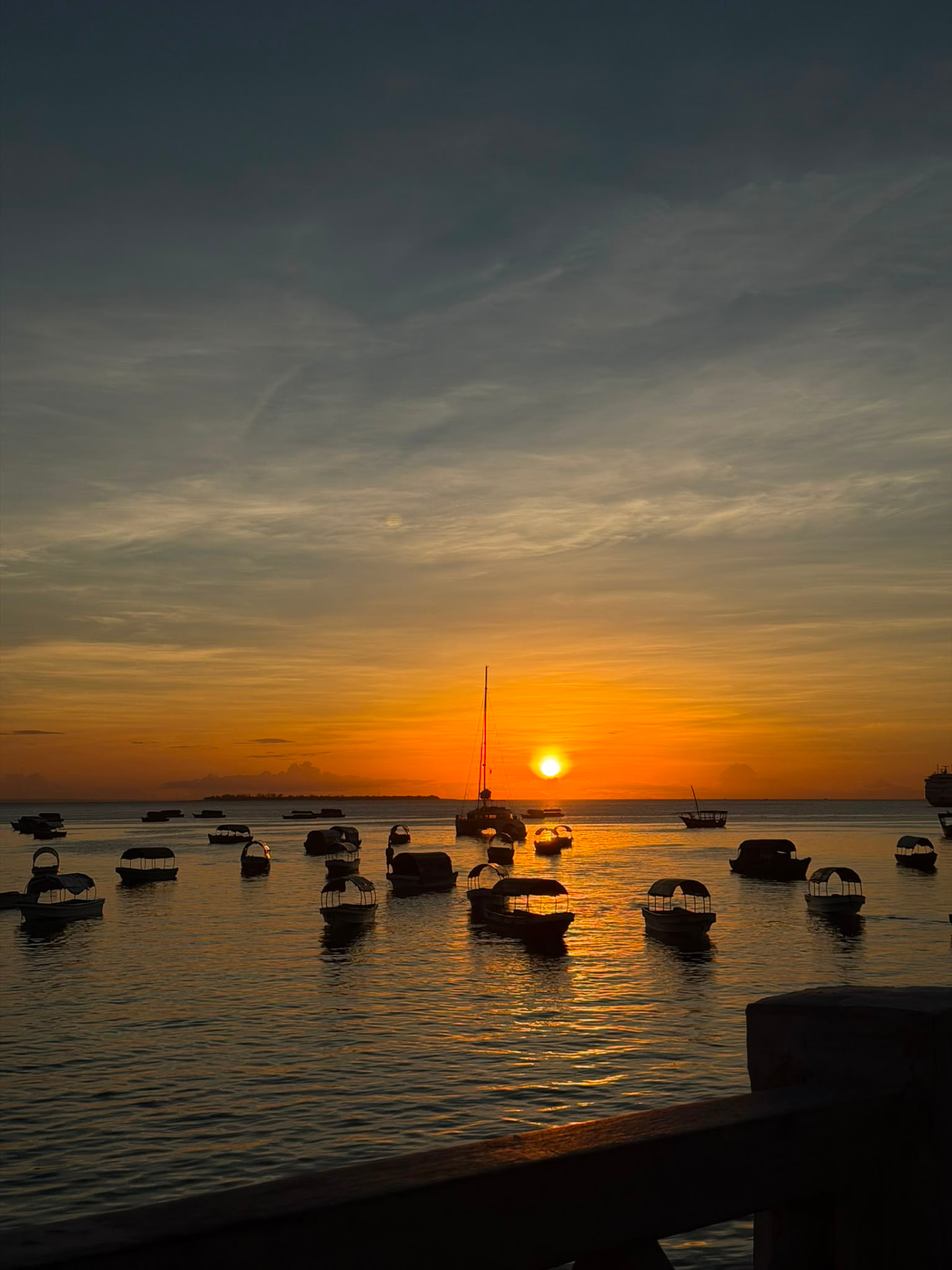 Golden hour sunset over the ocean with wooden boats resting on calm water